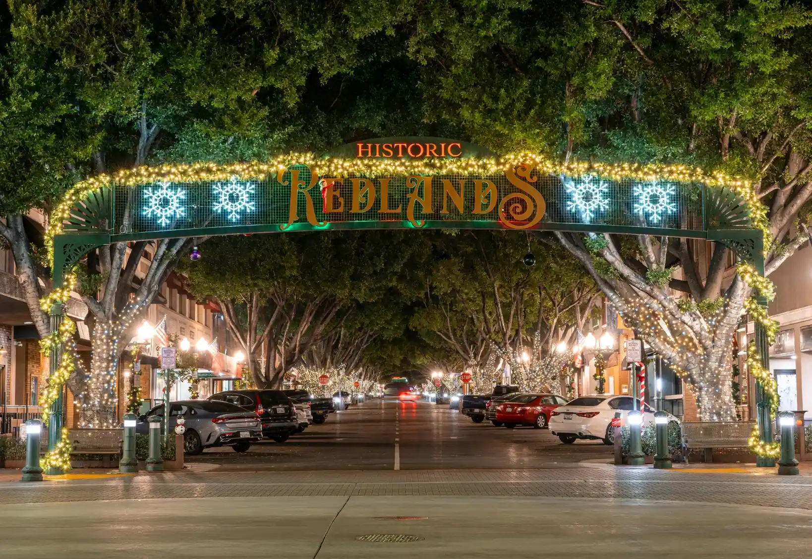 Historic Redlands downtown entrance arch decorated with holiday lights at night.