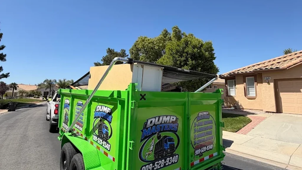 Bright green Dump Masters dump trailer parked on a residential street with debris loaded inside
