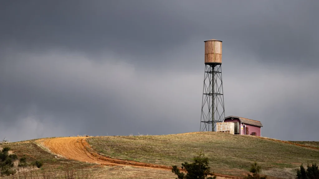 Dirt road leading past a water tower in a rural hillside landscape in Calimesa, CA